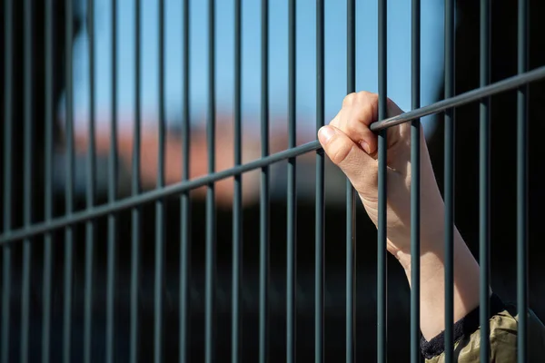 Рука дитини-біженця тримає металевий паркан — стокове фото