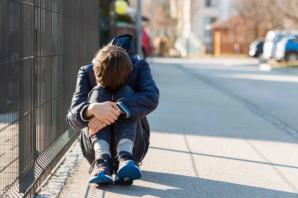 Szomorú fiú ül és sír az utcán. — Stock Fotó