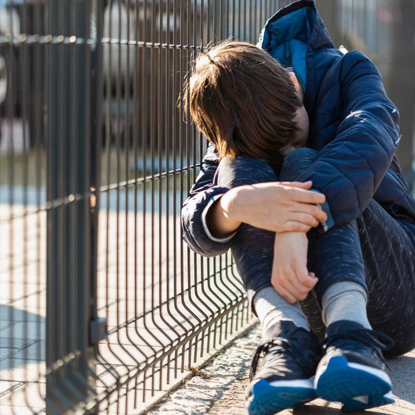 Üzgün çocuk sokakta oturup ağlıyor. — Stok fotoğraf