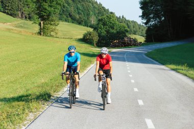 Doğada asfalt yolda giden profesyonel yarış motorcuları.