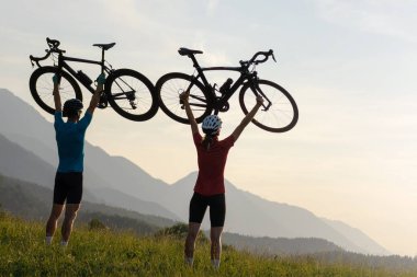 İki siluet başlarının üzerinde bisiklet tutuyor, kazanan poz veriyor