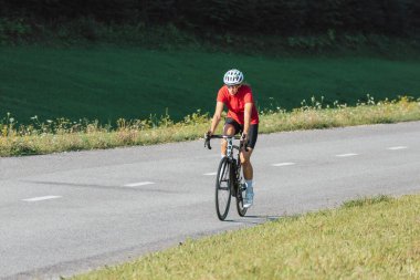 Açık yolda bisiklete binen yarış kıyafeti giyen kız.