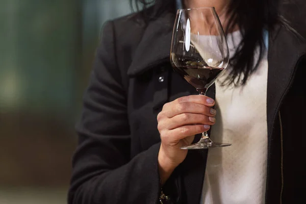 Woman tasting wine at the wine cellar with barrels in background