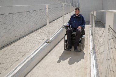 Man in a wheelchair use an accessible ramp.