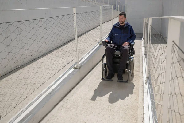 Man in a wheelchair use an accessible ramp.