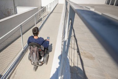 Man in a wheelchair use an accessible ramp.