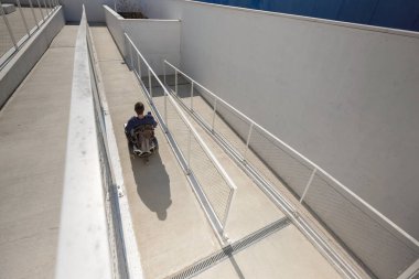 Man in a wheelchair use an accessible ramp.