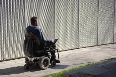 Man in a wheelchair use an accessible ramp.