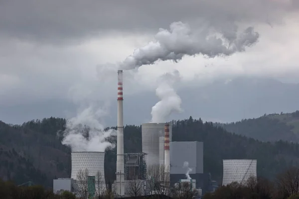 Overcast grey sky and toxic emissions released from a coal power station chimney. Energy industry, environmental and health issue concept.