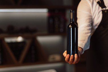 Şarap garsonu elinde bir şişe şarap tutuyor.