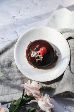 Çikolatalı kremalı pasta ve üstünde ahududu ve açık arkaplanda pembe gül. Eski ve lüks.