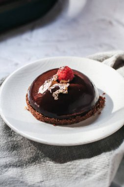 Çikolatalı kremalı pasta ve üstünde ahududu ve açık arkaplanda pembe gül. Eski ve lüks.