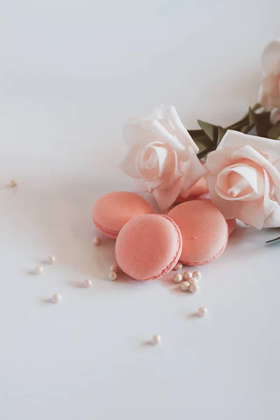 Pink macaroons with bouquet of rose on marble table, pastel colored, Traditional French multicolour macaroon. selective focus. Copy space