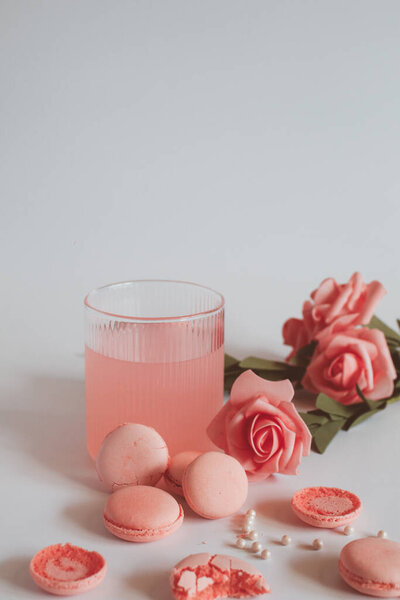 Pink macaron cookies and rose flowers on white background. French cookie. Soft pastel vintage tone. 
