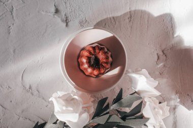 Güneş ışığı altında güllü Caneles de Bordeaux. Fransız pastası Canele romu ve vanilya aromalı kalın karamelli kabuk.
