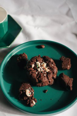 Yeşil tabakta taze ev yapımı çikolatalı kurabiyeler. Güzel kahvaltı. Çikolata parçalı geleneksel kurabiye yığını. Noel konsepti