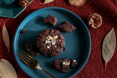 Yeşil tabakta çikolatalı Noel kurabiyeleri, kırmızı arka plan. Sıcak ev atmosferi. Şenlikli ev yapımı tatlılar.