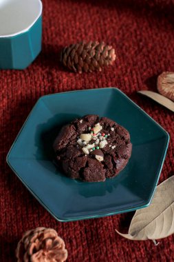 Yeşil tabakta çikolatalı Noel kurabiyeleri, kırmızı arka plan. Sıcak ev atmosferi. Şenlikli ev yapımı tatlılar.