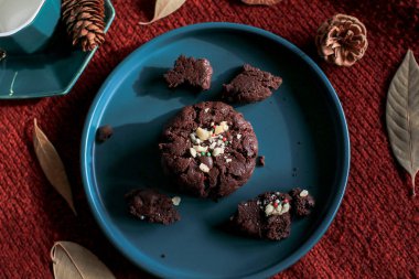 Yeşil tabakta çikolatalı Noel kurabiyeleri, kırmızı arka plan. Sıcak ev atmosferi. Şenlikli ev yapımı tatlılar.