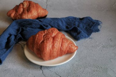 Gri arka planda taze pişmiş kruvasan. Fransız ve Amerikan kruvasanları ve fırınlanmış hamur işleri kahvaltı içindir..