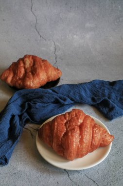 Gri arka planda taze pişmiş kruvasan. Fransız ve Amerikan kruvasanları ve fırınlanmış hamur işleri kahvaltı içindir..