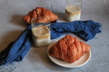 Kahvaltıda sıcak tereyağlı kruvasan ve kahve. Fransız ve Amerikan kruvasanları ve fırınlanmış hamur işleri. Sağlıklı beslenme ve tatlı yemek kavramı.
