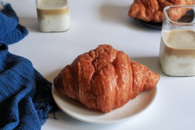 Kahvaltıda sıcak tereyağlı kruvasan ve kahve. Fransız ve Amerikan kruvasanları ve fırınlanmış hamur işleri. Sağlıklı beslenme ve tatlı yemek kavramı.