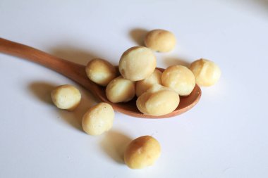 Beyaz arka planda tahta kaşıkta Macadamia fındıkları. Sağlıklı ürün. Macadamia fındıkları sağlıklı vitaminlerle dolu bir protein kaynağıdır..