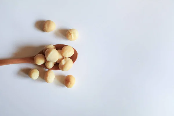 Macadamia nuts in wooden spoon on white background. Healthy product. Macadamia nuts are a source of protein packed with healthy vitamins.