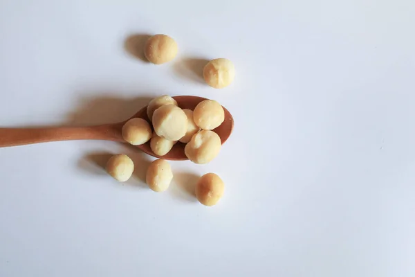 Macadamia nuts in wooden spoon on white background. Healthy product. Macadamia nuts are a source of protein packed with healthy vitamins.