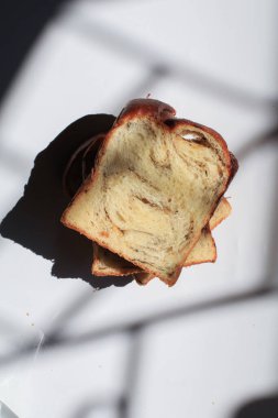 Pencereden sabah beyaz arka planda dilimlenmiş siyah mantar ve peynirli Brioche ekmeği..