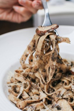 Restorandaki ahşap masada mantarlı ve kremalı spagetti. Lezzetli İtalyan füzyon makarnası.