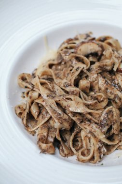 Restorandaki ahşap masada mantarlı ve kremalı spagetti. Lezzetli İtalyan füzyon makarnası.