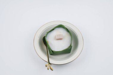 Homemade Thai Pudding with Coconut topping in banana leaf(Tako) on white background. Jelly coconut cream with corn and taro on top. Famous Thai desert ,