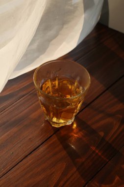 Hot tea cup on wooden table near white curtain window with nature sunlight in the morning.