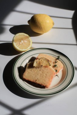 Beyaz arka planda güneş ışığı altında ev yapımı limonlu pasta. Kış tatili için lezzetli bir tatlı. Işık ve gölge.