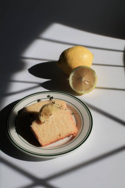 Beyaz arka planda güneş ışığı altında ev yapımı limonlu pasta. Kış tatili için lezzetli bir tatlı. Işık ve gölge.