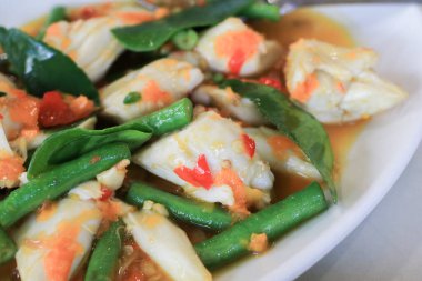 Baharatlı yengeç, fesleğenli ve beyaz tabakta sarı biberli kızartma. Asya Tayland mutfağı meşhurdur. sağlıklı deniz ürünleri.