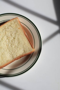 Sabah güneşinin altında beyaz tabakta ev yapımı kaygan ekmek. Kahvaltı ekmeği ve kahve..