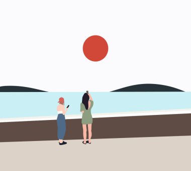 İki kadın turist nehrin kenarında gün batımının fotoğrafını çekiyor. Gezginler yaşam tarzı ve doğal kaynaklar