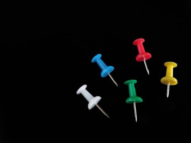 Koyu siyah arkaplanda çok renkli pin başparmak raptiyeleri izole