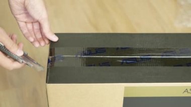 IZHEVSK, RUSSIA - 09 Ekim 2021: Karton kutunun üzerinde Asus logosu olan bandı kesen adam. Karton kutunun açılma süreci.
