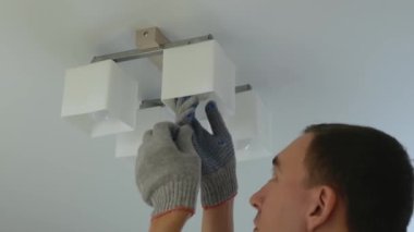 Man twist out light bulb on chandelier at home. Close up view on handyman changing light bulb under ceiling.