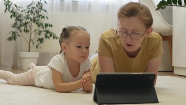 祖母为孙女读平板电子书 奶奶和孙女在一起 家庭中不同年龄的亲戚之间温暖关系的概念 — 图库视频影像