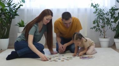 Küçük aile bulmacayı seçer ve evde yerde oturur. Sevimli küçük kız, genç anne ve babasıyla evde konuşuyor. Küçük kız ve genç anne ve baba birlikte vakit geçiriyorlar..