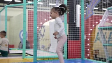Küçük kız eğlence ya da oyun merkezinde trambolinde zıplıyor. Küçük kız trambolindeki eğlence merkezinde eğleniyor..