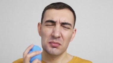 Diş ağrısı kavramı. Genç beyaz adam diş ağrısı ya da diş hastalığından dolayı yanağa acı veren bir ifadeyle buz koyuyor. İnsan acı hisseder ve kameraya bakar..