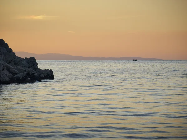 Rocha do mar e pescadores distantes — Fotografia de Stock