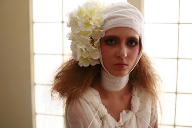 genç, kırılgan kız ayakta bir bornoz bandajlı bir kafa ile saçında hasta kırmızı çiçek