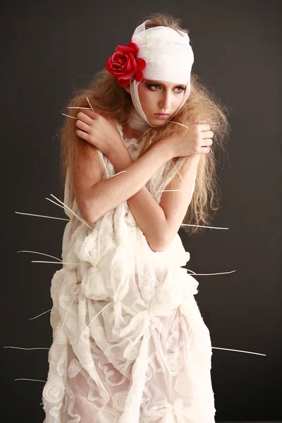 Chica joven y frágil de pie en un albornoz con una cabeza vendada, flor roja enferma —  Fotos de Stock